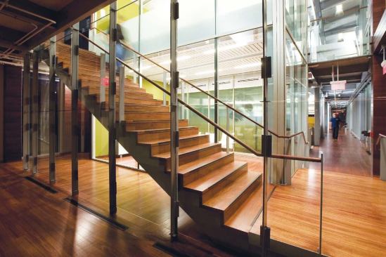 Hardwood complementing the mahogany of the exterior boardwalk continues inside, forming an interior boardwalk that follows the glazed façade. The same hardwood reappears on the staircases.