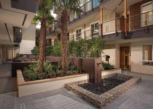 The courtyard features a linear fountain, a living green wall, an outdoor fireplace, barbecue grills, and a community garden.