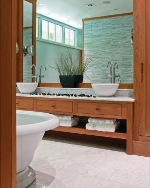 A symmetrical layout and abundant clerestory light give this master bath its serene sense of order. Watery green mosaic tile set in a sinuous pattern backdrops the freestanding vessel tub.