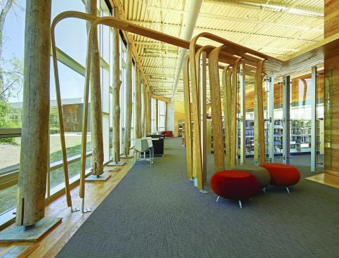 In addition to the natural wood columns, a bent-wood screen creates a sculptural point of interest, and serves the practical purpose of setting the reading room off from the stacks. Indirect light fixtures throughout create a diffused glow that provides enough light without straining the eyes of those reading, but during the day, natural light is the primary illumination in the space.