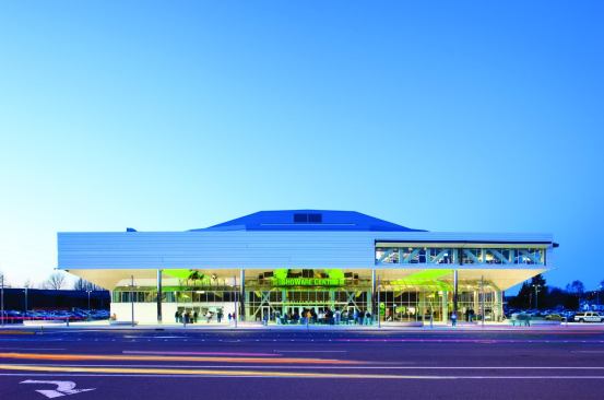 The second-floor cladding is composed of white 22 gauge metal panels. Staggering the panels, some of which are slightly recessed, adds texture to the surface. The swell of the roof—supported inside by massive steel trusses—is clad in a similar material with smaller-scale horizontal metal ribs.