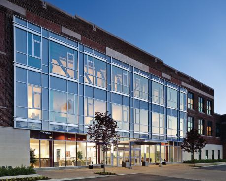 A curtain wall hangs where the auditorium once stood, providing deep daylight penetration.