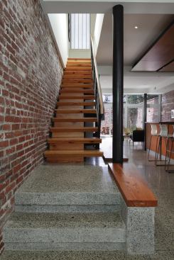 Concrete floors and spare metal detailing highlight the warm hues of a salvaged pine staircase.