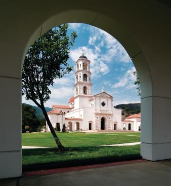 Our Lady of the Most Holy Trinity Chapel sits at the head of Thomas Aquinas College's arcaded academic quadrangle. The symbolic placement, combined with the 135-foot bell tower's stature as the tallest structure on campus, reinforces the church's important role in college life. A statue of Mary surmounts the chapel's pediment.