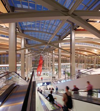 In the terminal (landside) building, exterior horizontal louvers also shade the interior. At night, the wooden ceiling is highlighted by ceramic metal halide uplights, surface mounted on the square structural columns of the main circulation spine.