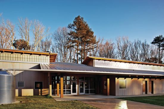 The entrance is located strategically on the building's northwest fa§ade. A double-height glazed wall opposite the front door frames a view down to the pond. To the left of the entrance is a corrugated rainwater cistern, fed by a gutter system that channels roof runoff. The water collected is used primarily for site irrigation.
