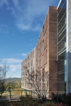 Split by a central service core, the six-story building has two canted wings. On the east façade these volumes are carefully placed to minimize views of the existing brick buildings slightly to the north.
