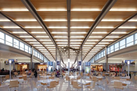 Travelers can relax and get something to eat in the concourse building’s food court. Primarily lit by daylight, electric light—linear 32W T8s—is concealed in the sweeping expanse of the wooden-slatted ceiling. Decorative pole luminaires outfitted with 24W compact fluorescent lamps add an accent of light to the bright and pleasant space.