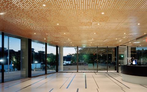 Large glass expanses coupled with a perforated wooden ceiling create a sense of openness in the ground floor public reception area. Fluorescent T5 tubes hidden behind the wood ceiling and a layer of white acoustic fabric along with the dot pattern creates a shimmering lighting effect. 
