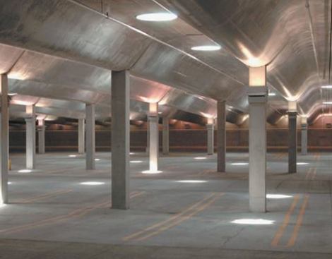 The parking garage is transformed into an unexpected art installation as light is allowed to permeate the below grade space through the circular skylights, part of the Walter De Maria sculpture above, One Sun / 34 Moons. Column wall sconces fitted with 250W metal halide lamps uplight the concrete ceiling.