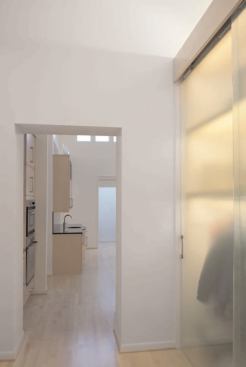 The entryway's special feature is a closet that takes on sculptural qualities with translucent-glass sliding doors, which diffuses the light from linear fixtures at each shelf. 