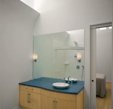 In the guest bath the “peeling” cove detail provides indirect light, while wall sconces at the mirror plane provide additional task lighting.
