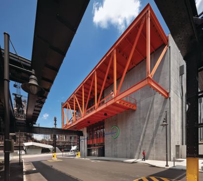 The west façade of the ArtsQuest Center is dominated by a steel balcony—a nod to the site's manufacturing roots—over one of the main entrances.