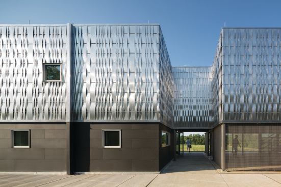 The strips of aluminum on the skin were hand-woven by Studio 804 students; the opaque base is clad in Hardie board from James Hardie. Many materials were donated by the manufacturers. 