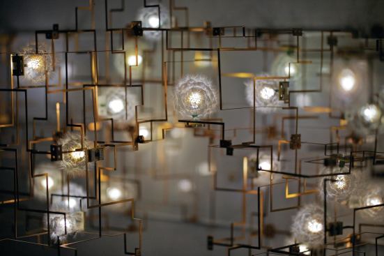 Fragile Future III (2011-2012), is an exploration of time and the dichotomy between nature and the man-made. For these modular works, Studio Drift builds a three-dimensional framework of bronze tubes and then inserts a series of LEDs, each of which has a hand-harvested dandelion seed glued to it. Each module uses three dandelions and measures 8 inches by 8 inches by 4 inches. Installations are composed of anywhere from three to 100 modules or more. Studio Drift uses the dandelion seeds becuase of the way in which they sensitively diffuse the LED light.