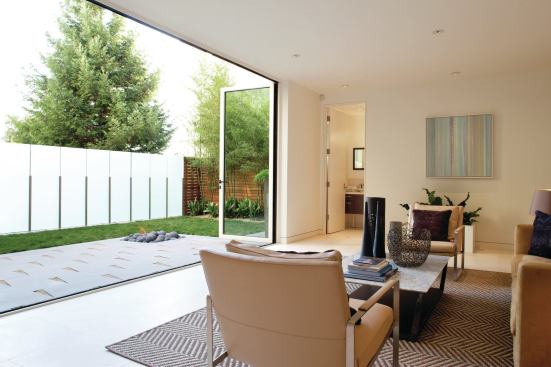 An etched glass privacy fence expands the lower-level family room to take in the compact backyard. A gas-fueled firepit provides an off-center focal point.