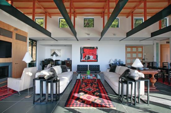Clerestory windows feed light from the uphill side of the living room through a wood-and-steel roof structure. 

