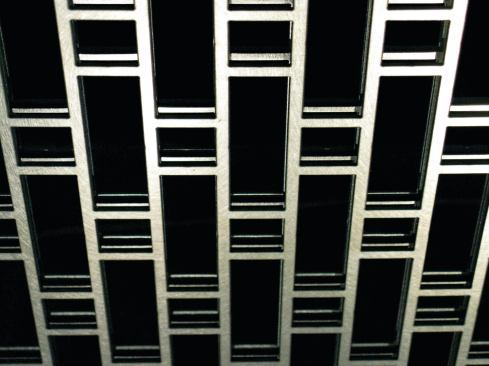 As designed by the Adaptive Building Initiative, in collaboration with metals fabricator A. Zahner Co., the steel layers within the kinetic shading system's panels can be rotated to assume patterns of varying visual complexity and opacity. The simplest arrangement, allowing the greatest amount of light, is a straightforward alignment of the layers ...