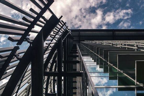 A view skyward shows fixed sunshades on the building's south façade (right), with vertical, aluminum reeds to block  solar gain on the west façade (left).