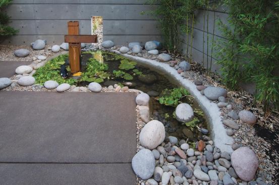 Decorative hardscaping mixed with a few plants and this rainwater collection water feature create a serene outdoor oasis that requires no irrigation and has no turf.