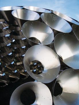 The maximum cone size was based on the largest available sheet of aluminum, and each piece was laser cut before being formed into the three-dimensional form. These cones were then grouped in subassemblies that were transported to the site where the pavilion was assembled. The cones on the bottom row were built to be filled with gravel and sealed, weighing down the structure and preventing uplift from winds on the site.