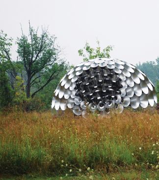 The reflectivity of the aluminum cones picks up the colors of the pavilion's environment. But the geometry of the cones themselves creates an interesting visual trick. The lower curve of each piece reflects the sky, and the upper curve reflects the ground plane, creating an inverse relationship with the surrounding landscape.