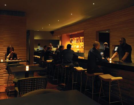 The acoustics in the space were a major consideration, especially with the anticipation of crowds of regulars, the performance of music, and the absence of many soft finishes. The solution was to mill strips of Baltic birch plywood and create a varied surface on the walls and the face of the bar. This creates a sculptural visual element, but also helps to diffuse sound.