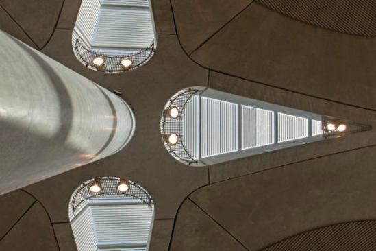 The raw interior surfaces of the concrete domes are left exposed, and the center of each is inscribed with a linear pattern. That pattern is echoed in the frit of the glass in each skylight. “We used body-tinted glass to carefully control the amount of light transmitted,” Parr says, and “a linear frit on the glass creates a play of light and shade internally, while combating glare.”