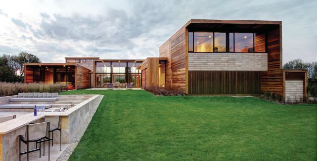 Courses of lapped travertine tiles below the end-wall windows contrast with the building’s flush mahogany siding.