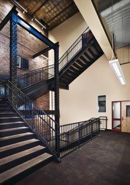 A central stair was added to provide circulation for students moving between floors. It is located in front of the restored coal chute and hung off original lattice beams. Where possible, the original structural elements were maintained, both to reinforce the building’s history and also to reduce new construction and renovation costs.