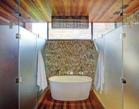A custom light fixture fabricated with bead chain echoes a panel of narrow vertical wall tile at the master bath’s tub.