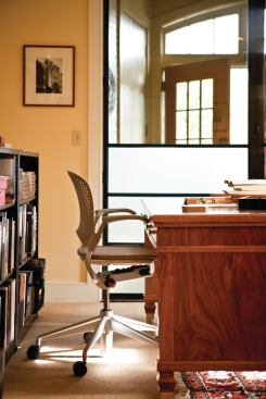 Elements such as salvaged wood and stone preserve the historic character of the space, but steel and glass doors add a modern touch and create a mini vestibule to the office.