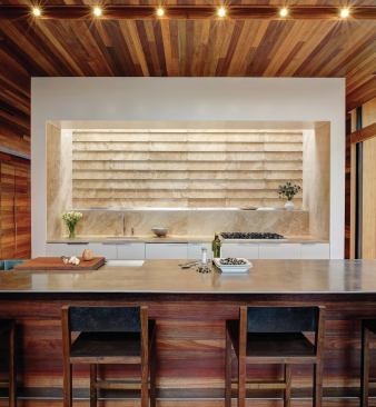 A linear skylight illuminates the travertine-lined cooking recess.
