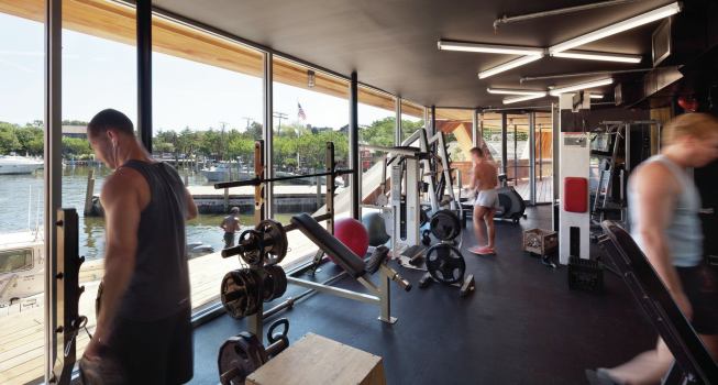 The gymnasium's floor-to-ceiling windows provide ample daylight while allowing patrons to look out over the harbor. 