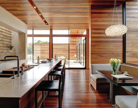 The island’s plate-steel countertop has a recessed drainboard that holds a removable cutting board. The custom pedestal table at the dining booth conceals power outlets for laptops and other personal electronic devices.