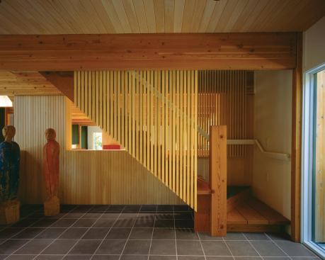 The stair combines massive timber elements with a slatted screen that seems to float above the floor.

