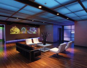 Exiting the elevators, guests enter a lobby area featuring a blue-hued ceiling and video walls.