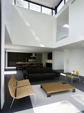 Despite having dark cabinets, the kitchen draws light from the adjacent double-heigh space and its clerestory windows.