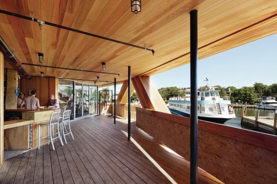 The first-floor terrace, with its outdoor bar, is lined with cedar on the floor, ceiling, and walls. A glass-enclosed gym overlooks the harbor. 