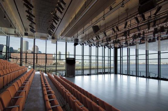 Theater: Curtain Wall

The north and west walls of the theater are uninterrupted glass surfaces. As principal Charles Renfro explains, "We wanted to work with the view, but not let it take over the building." The curtain-wall design went through several iterations, starting with a sheer glass-fin structure, with an additional layer of glass at the inner face of the fins to decrease noise from jet traffic at nearby Logan Airport. During the later stages of design, acoustic engineers decided the noise infiltration was insignificant, and the second glass layer was eliminated. (Ultimately, the glass fins were replaced by aluminum supports as a cost-saving measure.)

Nonetheless, each of the insulated glazing units that make up the single glass layer is composed of two thicknesses of glass, arresting different frequencies of sound as they pass through the wall. 