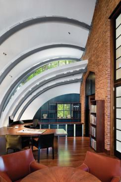 Bent steel tubes bolted into the former church's end wall support the zinc-clad structure, with overlapping panels allowing light to enter through upper clerestory windows. 
