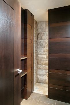 Stone clads this guest bath shower in three forms—large rough-hewn blocks segue into polished mosaics on the wall and smooth tiles on the floor. Dark cabinetry frames the pale variations in stone.