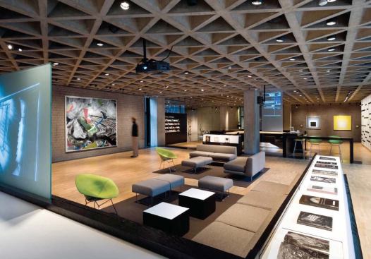 The new media lounge in the gallery's lobby, designed by Joel Sanders, is a flexible space where students can work and relax. The furniture can be easily stowed away when the gallery hosts events. A remote-controlled media screen (at left) rolls out of the L-shaped black cabinet for multimedia presentations.