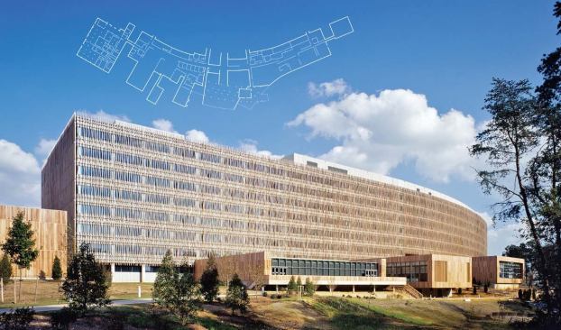 The Census Bureau building is clad in a brise soleil of wavy, laminated wood fins that are attached to a glass curtain wall, interrupted by concrete spandrels. The fins extend past the edges of the walls, creating a sinuous skin that breaks the box and enlivens the site.