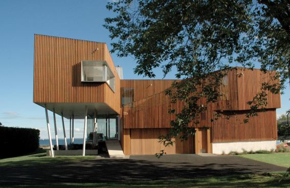 The Coastal Residence's wave pattern unfolds like a seashell, sheltering an interior courtyard. Its vertical cedar louvers are a twist on traditional board-and-batten siding. In contrast to the flat panoramic view from inside the elevated rectangle, the s