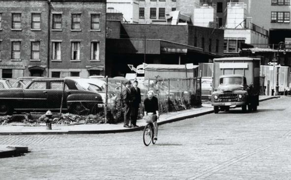 Urbanist Jane Jacobs in the 1960s rides her bike through a Manhattan neighborhood threatened by one of Moses' expressway projects. Jacobs fought Moses and won, triggering the nationwide shift toward community participation in urban planning.