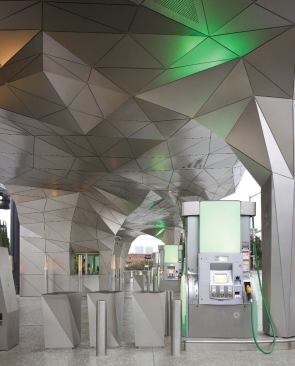 Not just an armature for the company logo, the canopy incorporates functional elements, such as the payment kiosk (in background), with colored lights directed against the underside to add further visual interest.