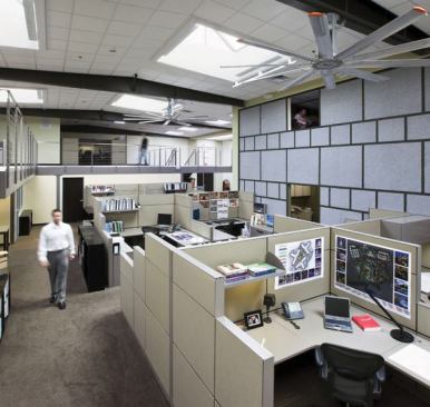 Lighting Design Alliance transformed what was once an auto parts warehouse into a luminous showcase for energy-efficient lighting design. Designed to meet LEED Platinum, daylight harvesting and dynamic dimming coupled with 10kW of photovoltaic panels on the roof reduce the lighting load to 0.07W per square foot. On the main façade, vertical louvers block west-facing light during the day but still allow ample natural light into the front office. Metal halide downlights illuminate the office entrance at night, while linear LED lightbars graze the textured stone surfaces (far left). The conference room (top right), is illuminated with natural light thanks to a full-height window wall. But at night the space is supplemented with a variety of electric sources—including color-changing LED covelights, direct-indirect fluorescent pendants, MR16 downlights, and compact fluorescent wallwashers—which are all dimmed separately with multiscene presets. In the work area (bottom right), concealed linear T5HO fixtures in clerestories provide general lighting. All the fixtures dim and are connected to photo cells, occupancy sensors, and a time clock. The skylights are tripled glazed for thermal heat gain and a clear north-facing window allows for full sky view. The 4-foot-by-4-foot skylights are equipped with suntracking mirrors and energy modeling software tracks energy savings.