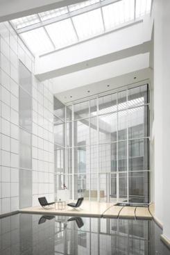 Natural light floods circulation paths through the clubhouse, which are dotted with seating areas and reflecting pools that echo the building’s aquatic surroundings.