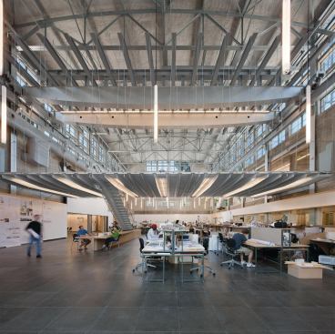 A stair linking the Crib to the floor below is supported on a single box girder that appears to peel down from the Crib’s floor system. The stair itself is a series of welded, bent steel plates, bracketed by a stainless steel railing and draped with steel mesh. Interior staircases lead from the studio level to offices and galleries above.